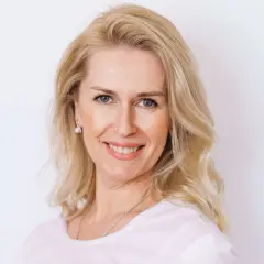 Uśmiechnięta blondynka po czterdziestce z fryzurą dodającą objętości cienkim włosom.