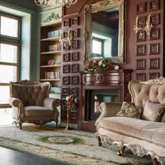Eleganckie wnętrze w stylu wiktoriańskim: aksamitne fotele, kanapa, kominek, lustro i regały z książkami tworzą przytulną atmosferę.