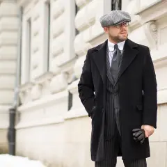 Elegancki mężczyzna w czapce i płaszczu, stylizacja inspirowana modą lat 40.