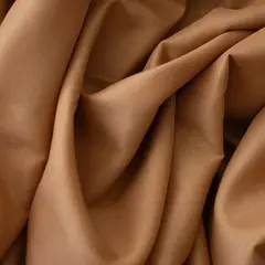 Gładka, brązowa krepa układa się w miękkie fałdy, tworząc elegancką fakturę.
