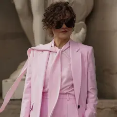 Elegancka kobieta w różowym garniturze i z burzą loków.