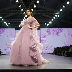 Modelka prezentuje suknię haute couture w kolorze pudrowego różu z falbanami na wybiegu.