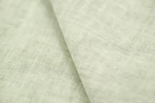 Miękki, jasnozielony len materiał z widoczną fakturą splotu.