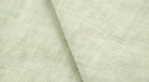 Miękki, jasnozielony len materiał z widoczną fakturą splotu.