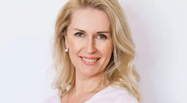 Uśmiechnięta blondynka po czterdziestce z fryzurą dodającą objętości cienkim włosom.