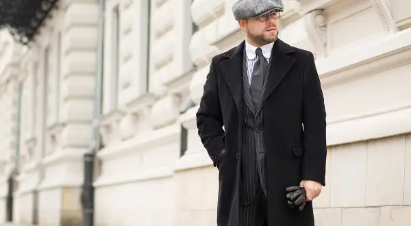 Elegancki mężczyzna w czapce i płaszczu, stylizacja inspirowana modą lat 40.
