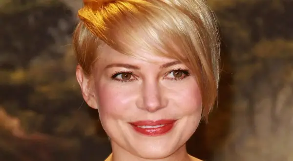 Uśmiechnięta kobieta z okrągłą twarzą i blond fryzurą, z grzywką zaczesaną na bok.