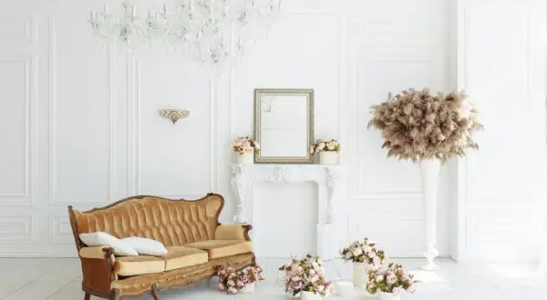 Elegancka kanapa w stylu francuskim, kryształowy żyrandol i bukiety kwiatów tworzą wytworny salon.