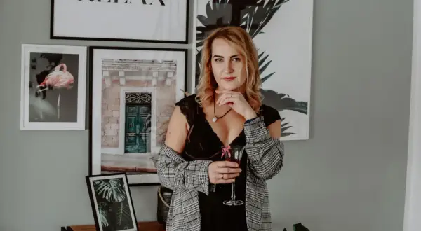 Kobieta w seksownej bieliźnie i marynarce, z kieliszkiem wina, wygląda jak bimbo gotowa na imprezę.