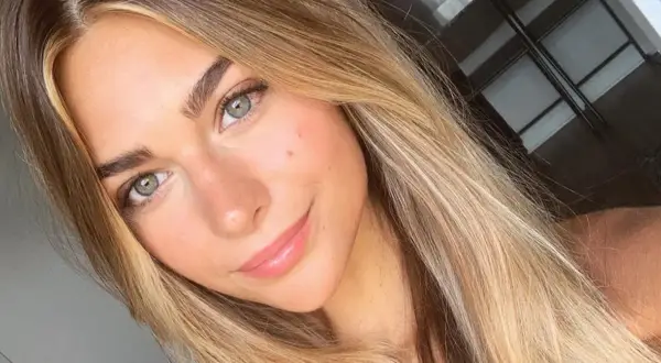 Uśmiechnięta dziewczyna z zielonymi oczami i włosami w odcieniu sombre blond.