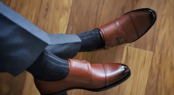 Eleganckie brązowe buty monk z klamrami i szare skarpetki w prążki do garnituru. Idealne połączenie, by zadać sobie pytanie: jakie skarpetki do garnituru?