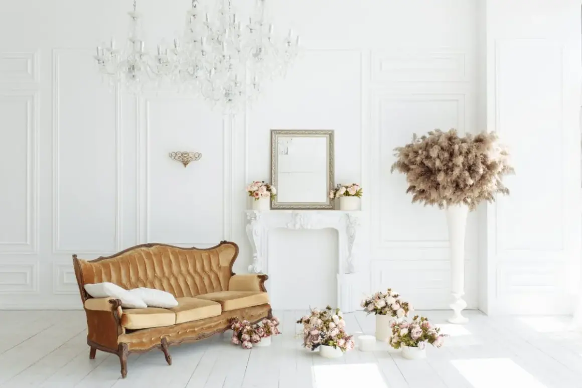 Elegancka kanapa w stylu francuskim, kryształowy żyrandol i bukiety kwiatów tworzą wytworny salon.