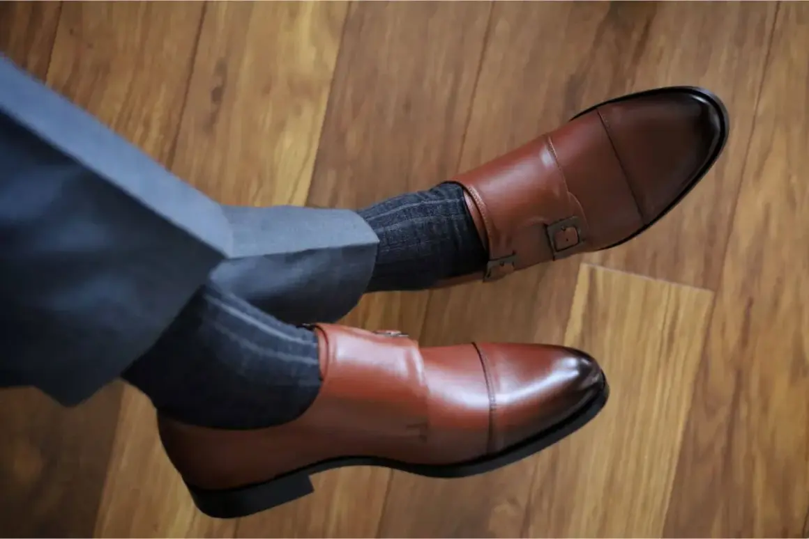 Eleganckie brązowe buty monk z klamrami i szare skarpetki w prążki do garnituru. Idealne połączenie, by zadać sobie pytanie: jakie skarpetki do garnituru?